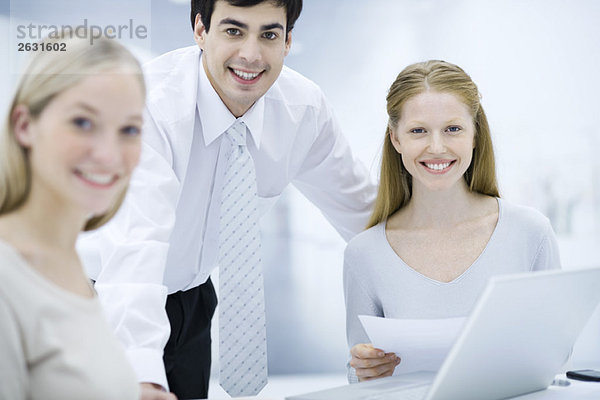 Büroangestellte lächeln vor der Kamera  eine Frau hält ein Dokument in der Hand