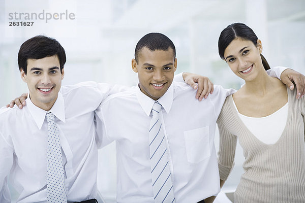 Drei junge Profis mit den Armen um die Schultern  lächelnd vor der Kamera.