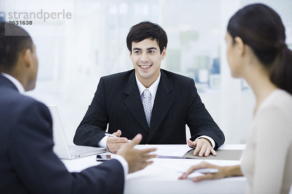 Geschäftsmann sitzt am Schreibtisch  spricht mit Kunden und lächelt