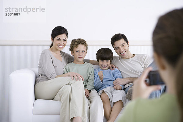 Familie sitzt auf dem Sofa  posiert für ein Foto von der Tochter