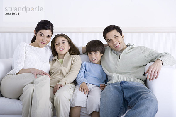 Familie mit zwei Kindern  die zusammen auf dem Sofa sitzen  Portrait