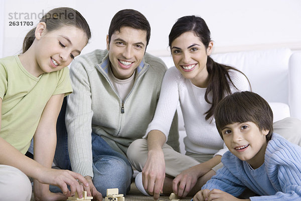 Familie spielt Dominosteine zusammen  lächelnd