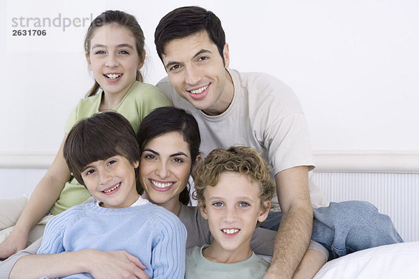 Eltern und drei Kinder lächeln vor der Kamera  Porträt