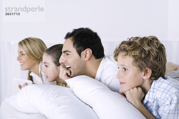 Familie auf dem Bett liegend  fernsehend  Seitenansicht