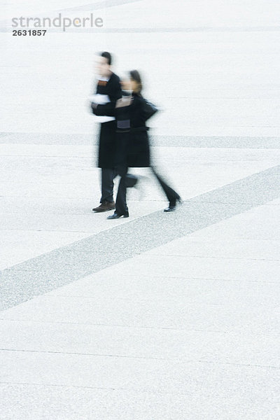 Geschäftsmann und Geschäftsfrau gehen gemeinsam über den öffentlichen Platz