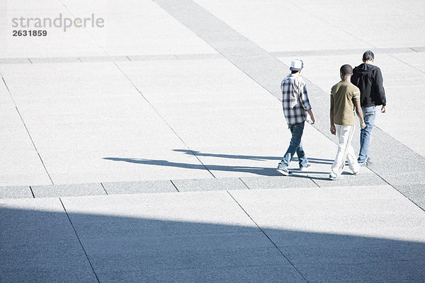 Junge Männer gehen gemeinsam über den öffentlichen Platz.