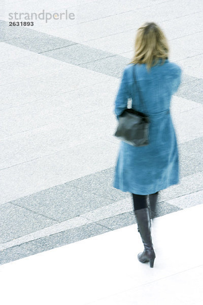 Frau in blauem Mantel absteigende Stufen im Freien