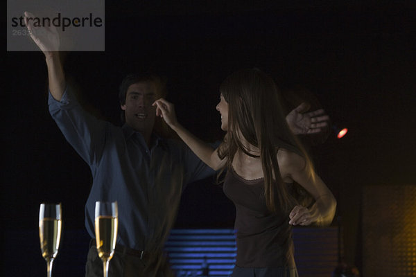 Paare tanzen im Nachtclub  Gläser Champagner im Vordergrund