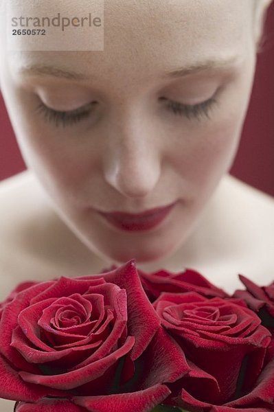 Junge Frau riecht an roten Rosen