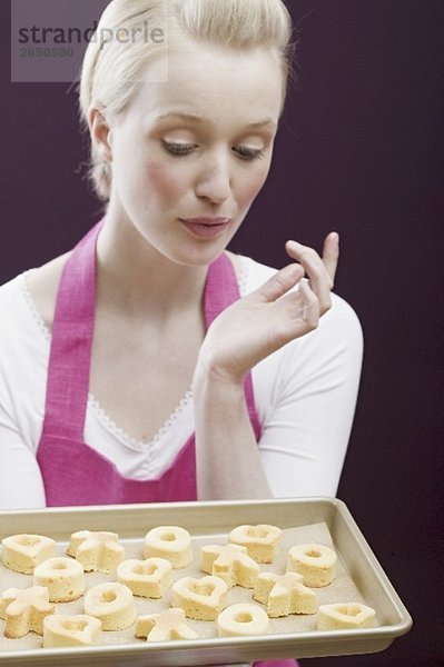 Junge Frau mit einem Backblech frisch gebackenen Keksen