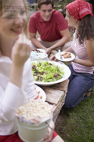 Junge Leute mit Popcorn und Salat beim Grillfest