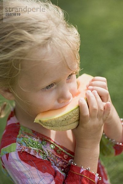Kleines Mädchen isst Melonenspalte