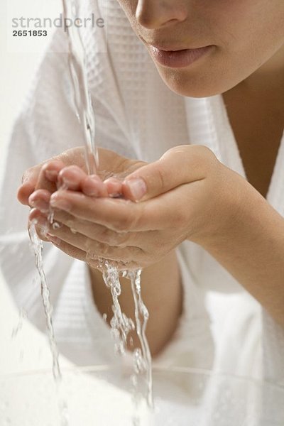 Frau hält ihre Hände unter Wasserstrahl