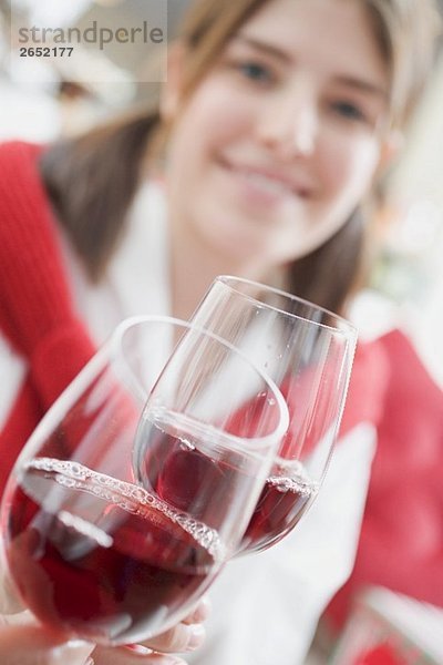 Junge Frau stösst mit Rotweinglas an zu Weihnachten