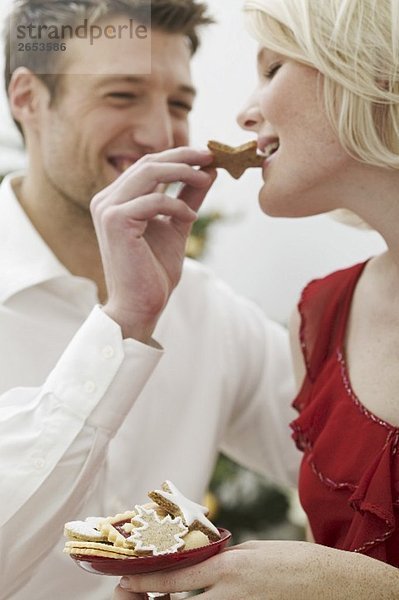 Mann füttert Frau mit Weihnachtsplätzchen