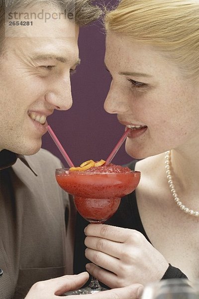 Romantisches Paar trinkt Strawberry Daiquiri aus einem Glas