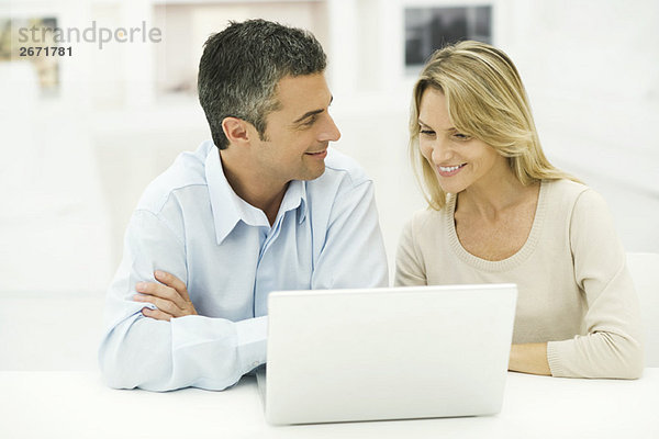 Paar mit Laptop-Computer zusammen  lächelnd