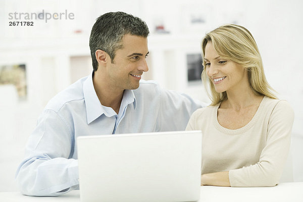 Paar mit Laptop-Computer zusammen  lächelnd