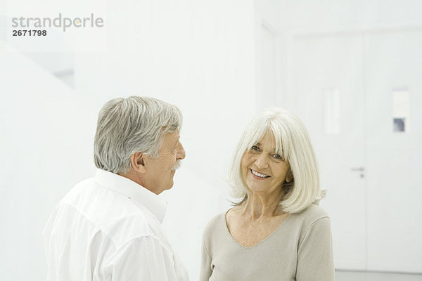 Seniorenpaar von Angesicht zu Angesicht stehend  Frau lächelnd vor der Kamera
