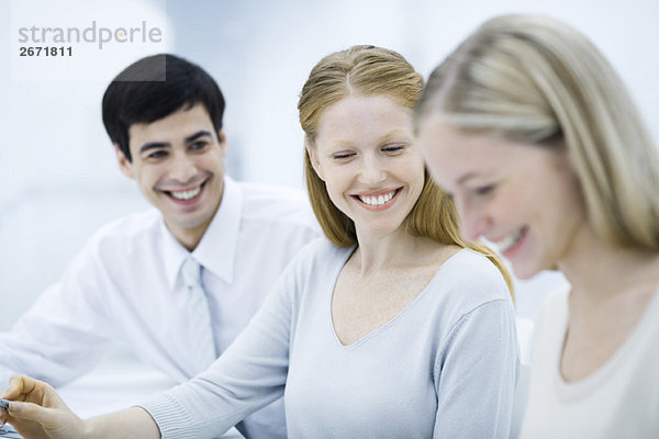 Junge Profis lächeln  Fokus auf Frau in der Mitte sitzend