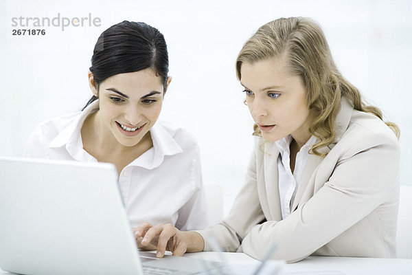 Professionelle Frauen  die zusammen auf den Laptop schauen  lächelnd