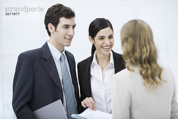 Geschäftsfreunde  die von Angesicht zu Angesicht stehen  lächelnd  eine Frau  die ein Dokument hält.