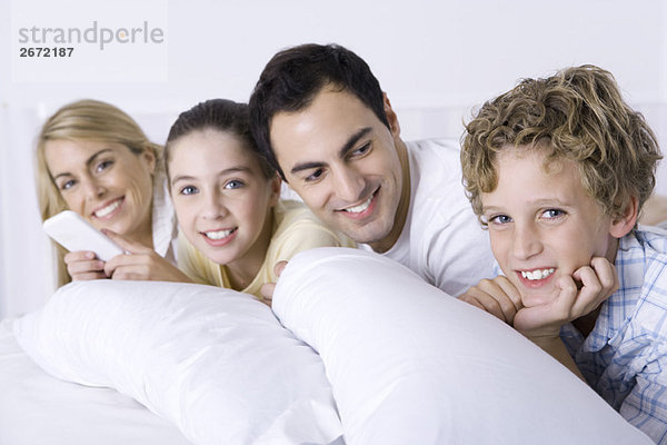 Familie entspannt sich zusammen im Bett  lächelt in die Kamera  Vater schaut auf Sohn