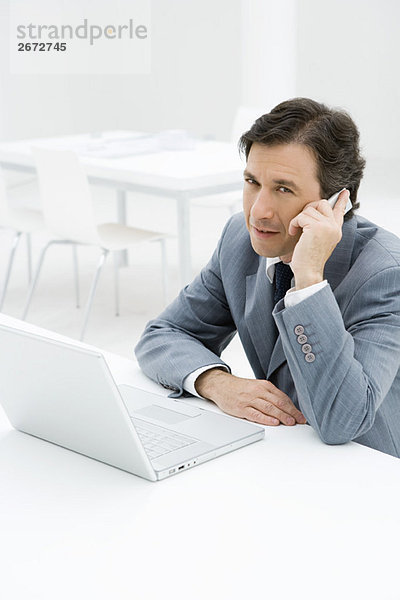 Geschäftsmann im Gespräch am Handy  am Laptop sitzend