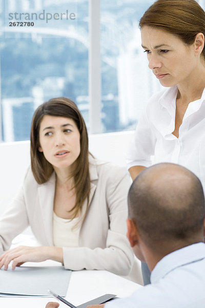 Profis mit einem Meeting am Schreibtisch  Schwerpunkt: stehende Frau