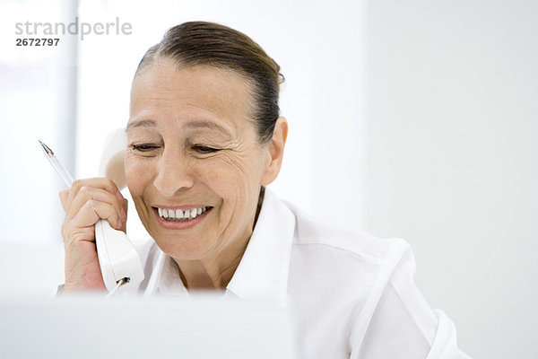Seniorin mit Festnetztelefon  lächelnd