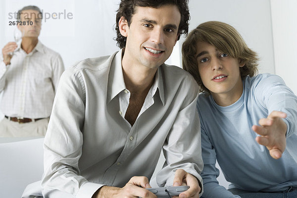 Junger Mann und jugendlicher Bruder spielen Videospiel  Blick auf Kamera