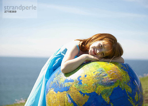 Junges Mädchen auf einem aufblasbaren Globus liegend