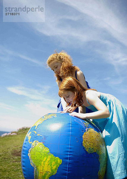 2 Mädchen schauen auf den aufblasbaren Globus