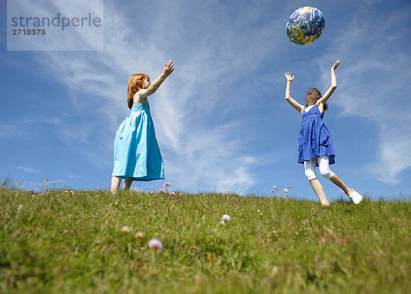2 junge Mädchen werfen aufblasbaren Globus