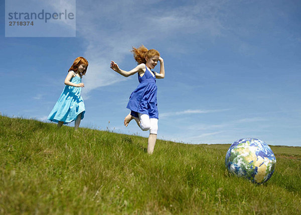 2 junge Mädchen laufen mit Ball (Globus)