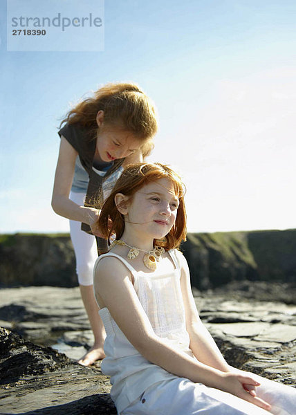 Mädchen setzt Muschelkette auf Schwester