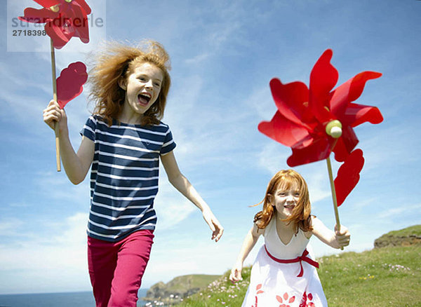 2 Mädchen lachen mit roten Windmühlen