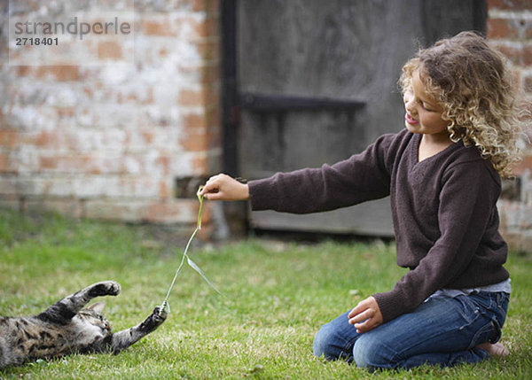 Junges Mädchen spielt mit Katze draußen