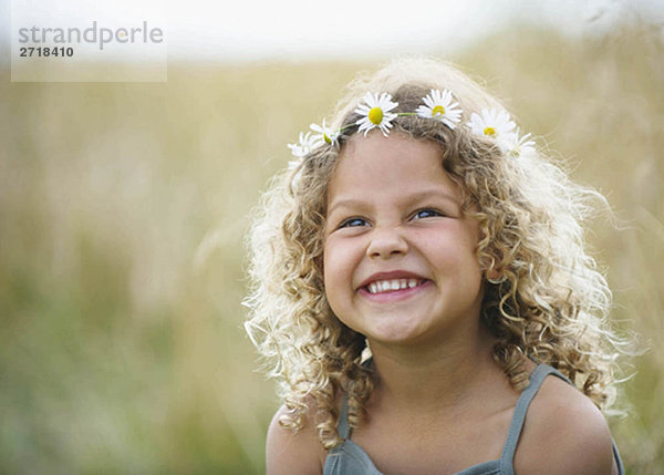 Junges Mädchen lacht mit Gänseblümchen im Haar