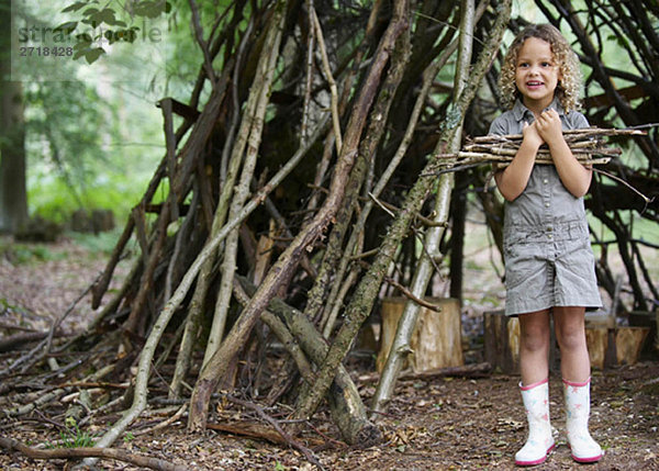 Junges Mädchen mit Zweighaufen im Wald