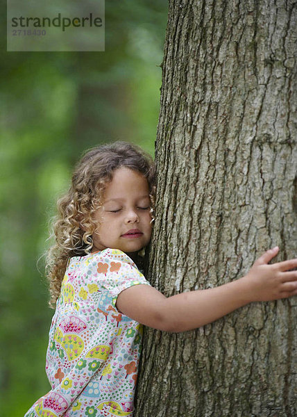 Junges Mädchen umarmt Baumaugen geschlossen