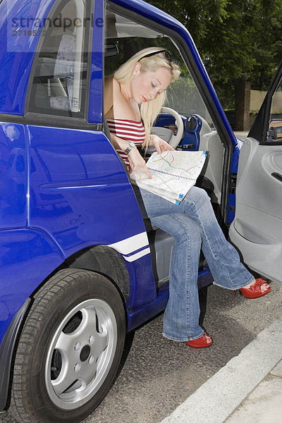 Junge Frau liest Karte im Elektroauto
