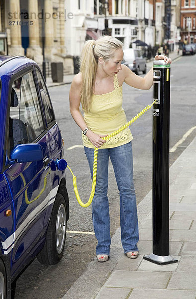 Junge Frau beim Aufladen eines Elektroautos