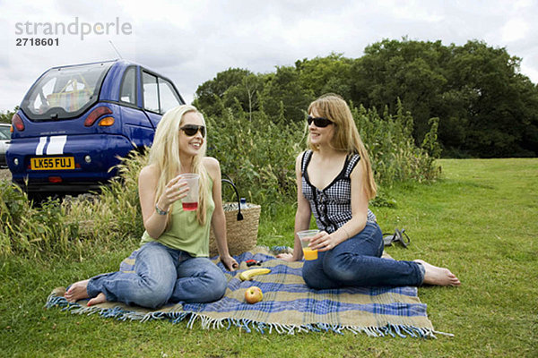 Junge Frauen picknicken mit dem Elektroauto