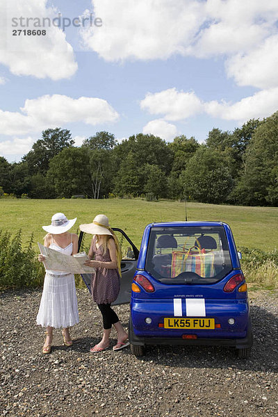 Junge Frauen mit Karte mit Elektroauto