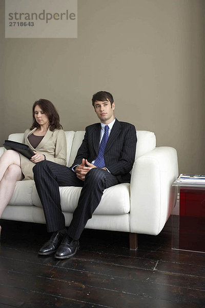 Geschäftsmann und Frau auf dem Sofa sitzend