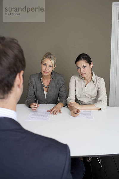 2 Geschäftsfrauen interviewen Mann