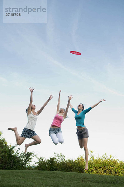 Teenager-Mädchen springen  um einen Frisbee zu fangen.