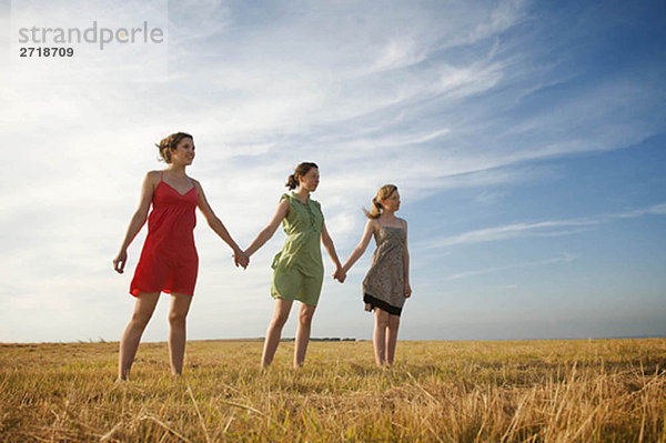 Drei Teenager-Mädchen halten sich an den Händen.