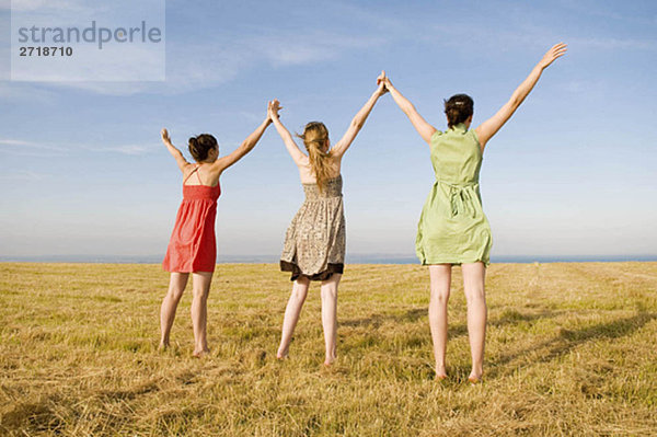 Drei Teenager-Mädchen halten die Hände hoch.